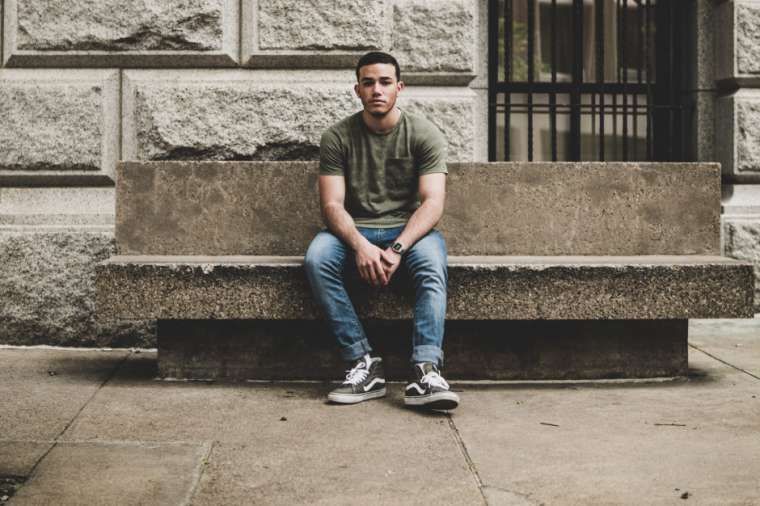 Young man sitting on bench outside social welfare office